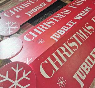Handpainted Christmas Fair signs by Robotmother.  White writing on red painted wood, wtih some simply dingbat snowflakes