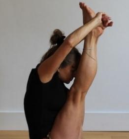A yoga pose with legs straight up and hand hoilding the legs. Head is resting on calves.